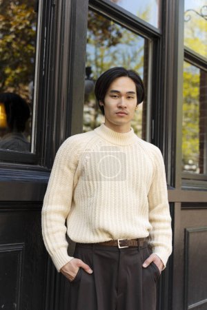 Téléchargez les photos : Portrait d'homme d'affaires asiatique attrayant debout à l'extérieur, regardant la caméra. Japonais modèle masculin dans des vêtements décontractés élégants posant pour l'image sur le campus universitaire - en image libre de droit
