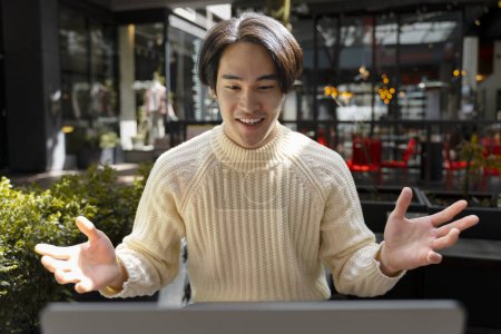 Téléchargez les photos : Bel homme asiatique souriant en utilisant la communication ordinateur portable en ligne ayant appel vidéo. Succès influenceur enregistrement vidéo. Étudiant japonais étudiant, ayant des leçons en ligne, concept d'éducation - en image libre de droit