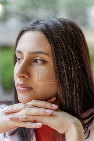 Photo for Portrait of pensive Indian woman looking away waiting someone on the street while sitting at the cafe. People lifestyle concept - Royalty Free Image