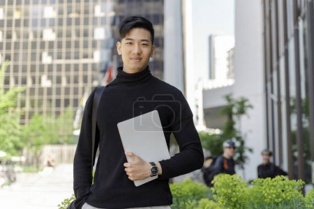 Photo for Confident asian businessman holding digital tablet, looking at camera on street, outdoors. Smiling chinese student studying near university campus. Education concept - Royalty Free Image