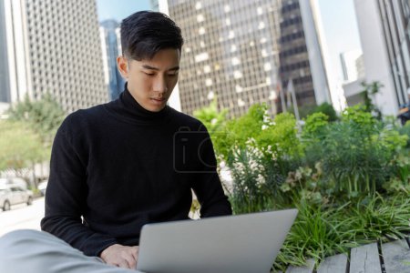 Téléchargez les photos : Pensive asiatique pigiste à l'aide d'un ordinateur portable, travail à distance sur le lieu de travail extérieur. Étudiant chinois attrayant étudiant, concept d'éducation en ligne - en image libre de droit