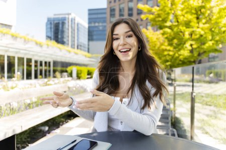 Photo for Beautiful woman having video conference, explaining, looking at camera. Attractive female student studying online, video conference. Successful businesswoman working at workplace in modern office - Royalty Free Image