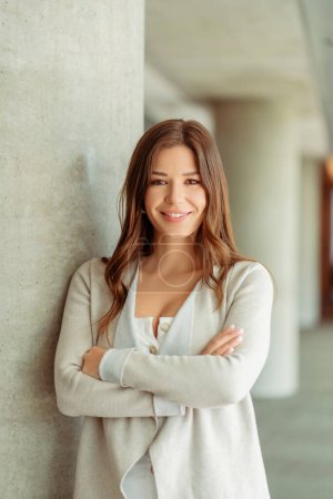 Photo for Portrait of smiling brunette saleswoman with long hair and crossed arms looking at camera. Confident stylish businesswoman working in modern office, successful business concept - Royalty Free Image