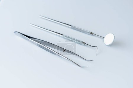 Photo for Sterile dental instruments lying isolated on gray background. Mirror, scraper and tweezers for dental treatment, surgery. Health care concept - Royalty Free Image