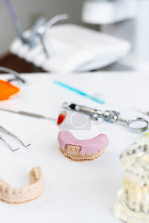 Foto de Oficina dental, yeso de dientes, dientes postizos, implantes, herramientas dentales en el lugar de trabajo. Medicina moderna de oficina. Concepto de asistencia sanitaria - Imagen libre de derechos