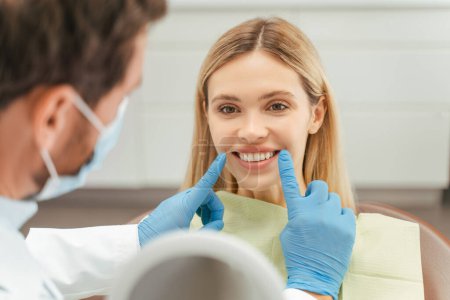 Téléchargez les photos : Portrait de jeune femme séduisante avec le sourire des dents assis dans la chaise dentaire, dentiste vérifier les dents. Patiente avec sourire en dentisterie moderne. Concept de soins dentaires - en image libre de droit