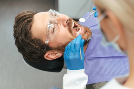 Téléchargez les photos : Dentiste examinant le patient dans une clinique dentaire moderne. Traitement des dents, soins de santé, concept d'hygiène buccodentaire - en image libre de droit