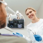 Portrait of smiling professional dentist talking with patient in modern dental clinic. Health care, oral hygiene concept 