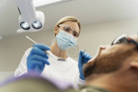 Photo for Professional dentist examining patient in modern dental clinic. Teeth treatment, health care, oral hygiene concept - Royalty Free Image