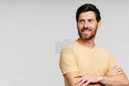 Téléchargez les photos : Portrait d'un bel homme barbu souriant aux cheveux élégants, portant des vêtements décontractés regardant loin après le service de salon de coiffure, isolé sur fond gris - en image libre de droit
