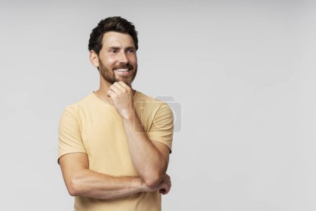 Foto de Guapo hombre barbudo sonriente mirando la cámara aislada sobre fondo gris. Confiado hipster moderno con el pelo con estilo después del servicio de barbería - Imagen libre de derechos