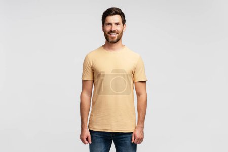Photo for Portrait of smiling handsome bearded man, hipster wearing blank t shirt looking at camera isolated on gray background. Happy successful fashion model posing for pictures, studio shot. Mockup - Royalty Free Image