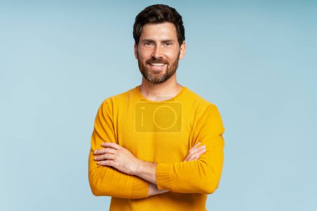 Photo for Handsome smiling bearded man wearing t shirt looking at camera isolated on blue background. Confident modern hipster with stylish hair after barbershop service - Royalty Free Image