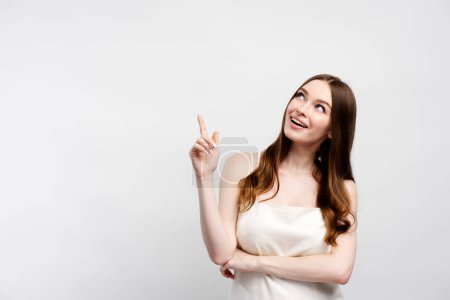 Photo for Cute elegant smiling woman in dress pointing with finger on copy space, place for text looking away. Attractive female posing isolated on gray background. Shopping concept, discount, advertisement - Royalty Free Image