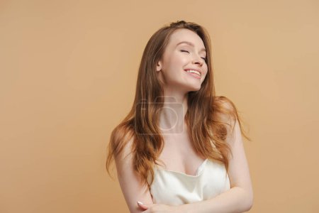 Photo for Portrait of sexy attractive woman with long healthy hair wearing nightgown isolated on beige background. Beautiful female closed eyes with smile posing alone. Healthy lifestyle concept - Royalty Free Image