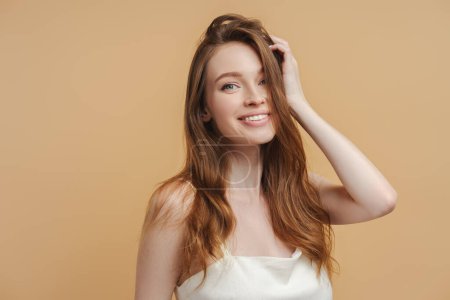 Photo for Portrait of sexy attractive woman with long healthy hair wearing nightgown posing isolated on beige background. Beautiful female with toothy smile looking at camera. Healthy lifestyle concept - Royalty Free Image