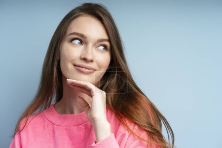 Photo for Portrait of cute smiling woman with beautiful long hair smiling and looking away isolated on blue background, closeup. Natural beauty, skin care - Royalty Free Image