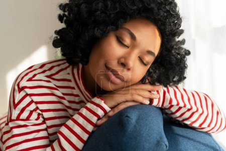 Photo for Portrait of beautiful African American woman sitting on comfortable sofa, eyes closed, sleeping at home. Attractive curly female posing for picture. Relaxation concept - Royalty Free Image