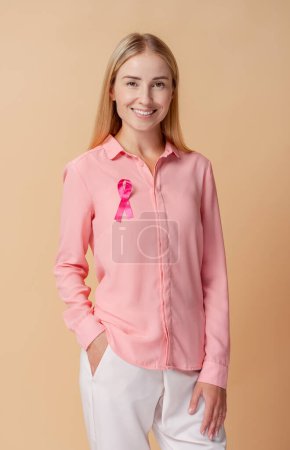 Foto de Mujer sonriente con cinta rosa aislada sobre fondo. Salud. Mes de sensibilización sobre el cáncer de mama - Imagen libre de derechos