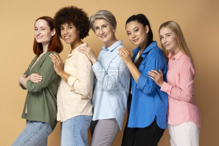 Foto de Grupo de hermosas mujeres multirraciales sonrientes con elegantes camisas de colores, abrazándose entre sí - Imagen libre de derechos