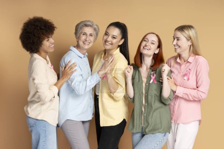 Foto de Grupo de mujeres multiétnicas con cáncer de mama cinta rosa se apoyan mutuamente aislados en el fondo - Imagen libre de derechos