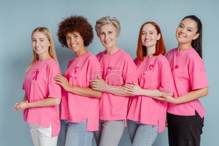 Foto de Grupo de mujeres sonrientes con cinta rosa abrazándose aisladas en el fondo. Concientización sobre el cáncer de mama - Imagen libre de derechos