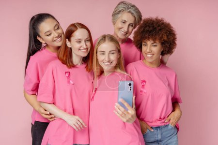 Foto de Mujeres sonrientes con cinta rosa grabando vídeo aislado de fondo. Concientización sobre el cáncer de mama - Imagen libre de derechos
