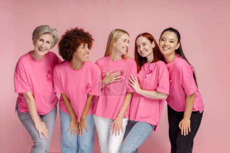 Foto de Mujeres sonrientes con comunicación de cinta rosa aisladas sobre fondo rosa. Concientización sobre el cáncer de mama - Imagen libre de derechos