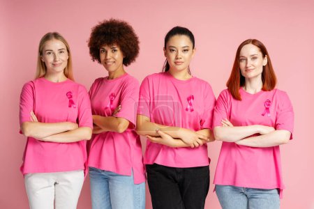 Foto de Mujeres sosteniendo el brazo cruzado usando camisetas con cinta rosa. Concepto mensual de concienciación sobre el cáncer de mama - Imagen libre de derechos