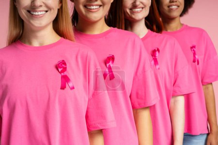 Foto de Mujeres sonrientes multirraciales que usan camisetas con cinta rosa de cáncer de mama aisladas en el fondo - Imagen libre de derechos
