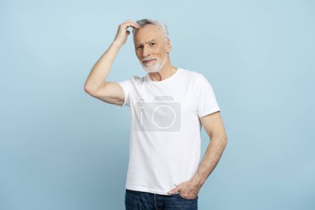 Photo for Serious pensive senior man wearing casual clothes thinking, planning isolated on blue background, mockup. Attractive male touching head, concept of business - Royalty Free Image
