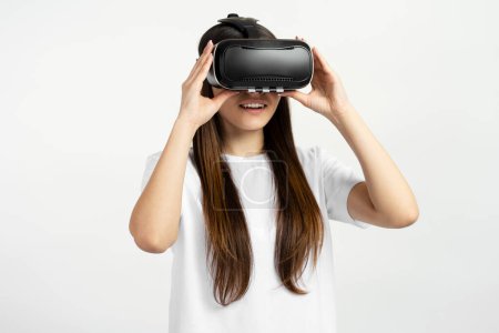 Téléchargez les photos : Jeune adolescente excitée utilisant des lunettes de réalité virtuelle isolées sur fond blanc. Technologie, concept d'innovation - en image libre de droit