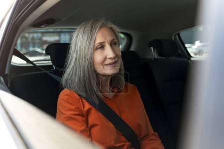 Téléchargez les photos : Portrait de personne âgée confiante et souriante avec ceinture de sécurité assise à l'intérieur d'une voiture confortable. Road trip, concept de transport - en image libre de droit