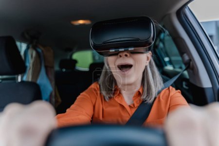 Foto de Retrato de mujer mayor emocionada con gafas de realidad virtual, coche de conducción con la boca abierta. Concepto de innovación - Imagen libre de derechos