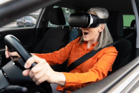 Foto de Emocionada mujer mayor con gafas de realidad virtual, coche de conducción. Concepto de innovación - Imagen libre de derechos