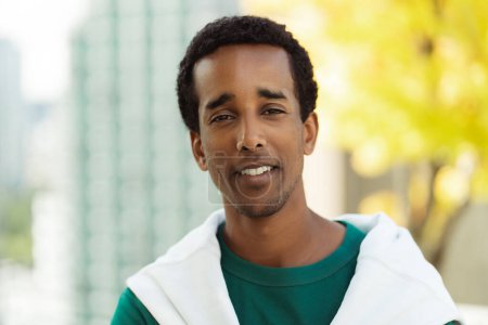 Photo for Closeup of handsome smiling african american man looking at camera, outdoors in park. Attractive young student standing near university campus, advertisement, education concept - Royalty Free Image