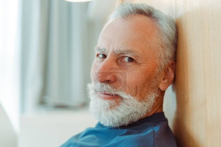 Téléchargez les photos : Portrait d'un séduisant homme âgé souriant avec barbe en t-shirt regardant la caméra, gros plan. Beau modèle masculin posant pour l'image, l'espace de copie. Concept de publicité, service client - en image libre de droit