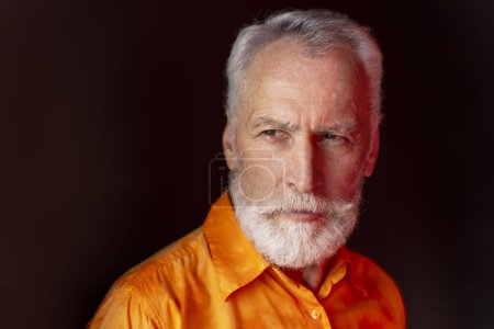 Photo for Portrait of handsome serious senior man with beard wearing stylish shirt looking away isolated on black background. Modern senior hipster posing for picture. Shopping concept - Royalty Free Image