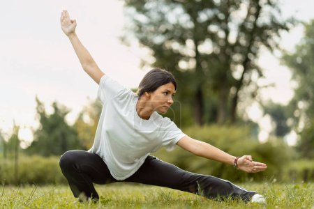 Foto de Retrato de una mujer seria usando entrenamiento de ropa deportiva, practicando wushu en el parque. Vida sana, kungfu, concepto de artes marciales - Imagen libre de derechos
