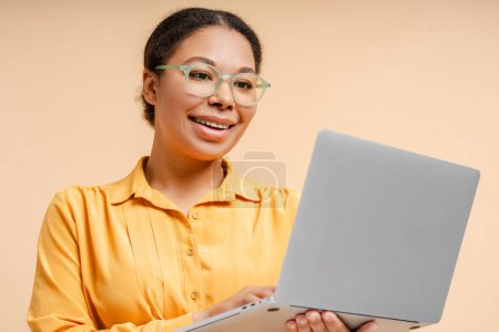Téléchargez les photos : Belle femme afro-américaine portant des lunettes tenant ordinateur portable, communication, travail en ligne, ayant un appel vidéo. Technologie, concept de vidéoconférence - en image libre de droit