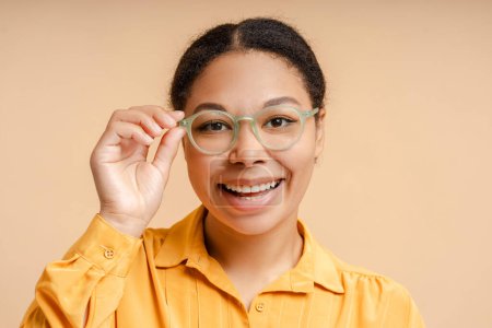 Foto de Retrato de una hermosa mujer afroamericana sonriente con gafas con estilo mirando a la cámara aislada en el fondo. Concepto de visión - Imagen libre de derechos