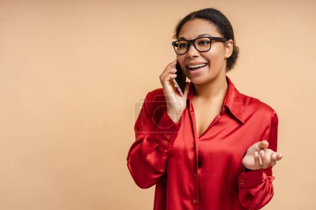 Téléchargez les photos : Portrait d'une belle femme d'affaires afro-américaine souriante parlant sur un téléphone portable, répondant à un appel en regardant loin sur un fond isolé. Concept d'entreprise réussi - en image libre de droit