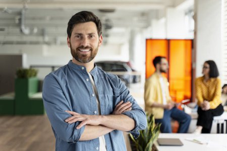 Photo for Portrait of a Caucasian confident middle aged bearded man, sales manager smiling looking at camera, posing with his arms crossed in the modern office interior. People. Teamwork. Business. Career. - Royalty Free Image