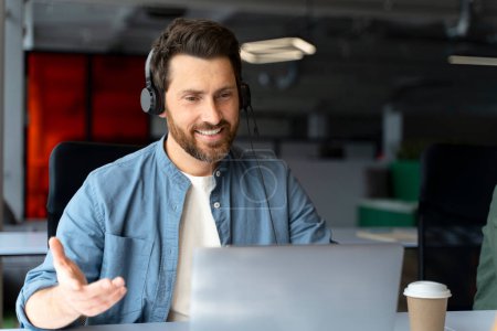 Caucasian middle aged handsome bearded man, successful experienced manager in HR department, recruiter wearing audio headset, smiling to his interlocutor while conducts job interviews via video link