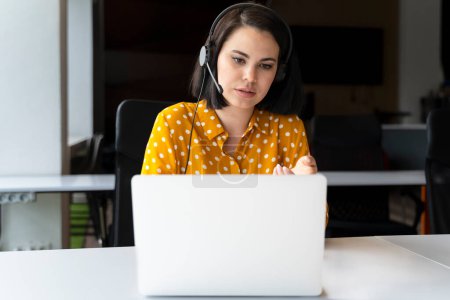 Caucasian young businesswoman, sales manager in audio headset, using laptop, talks with investors during online meeting video conference. People. Business. Career. Communication across the distance