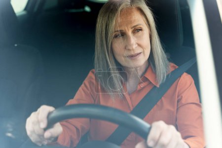Téléchargez les photos : Triste femme âgée fatiguée conduisant une voiture coincée dans la circulation. Concept de transport - en image libre de droit
