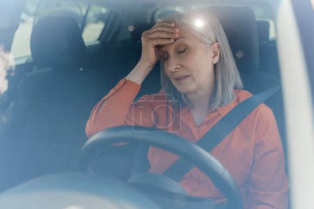 Gestresste Seniorin am Steuer eines im Stau stehenden Autos. Unzufriedene Frauen mit Kopfschmerzen. Verkehrskonzept 