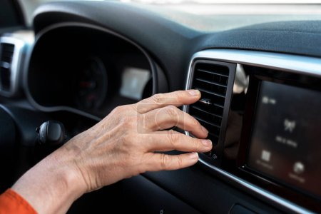 Foto de Primer plano de la mano de la mujer usando el aire acondicionado sentado dentro del coche nuevo, enfoque selectivo - Imagen libre de derechos