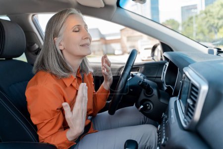 Foto de Mujer mayor sonriente usando aire acondicionado, control climático sentado dentro de un coche nuevo. Concepto de transporte - Imagen libre de derechos