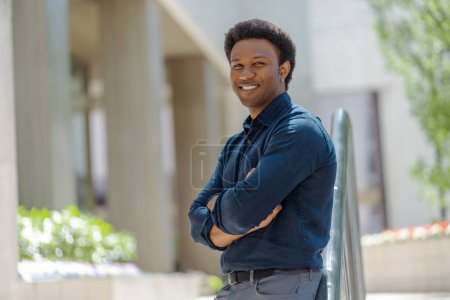 Foto de Sonriente hombre afroamericano guapo con los brazos cruzados mirando al aire libre, espacio de copia. Retrato del hombre de negocios con ropa formal parado en la calle - Imagen libre de derechos